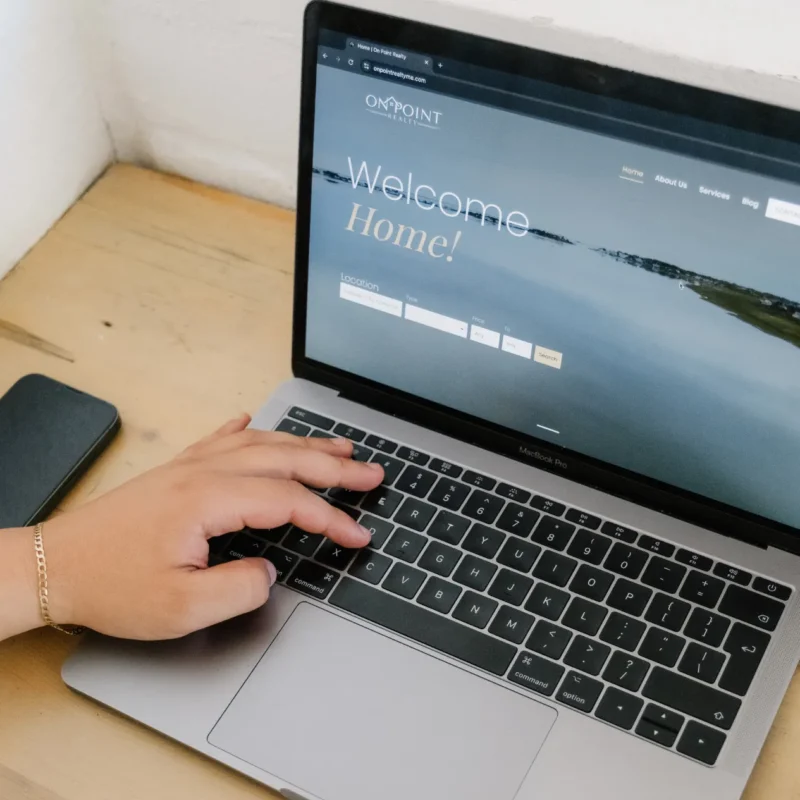 a person, not fully showing, scrolling through On Point Realty's homepage of their website that Don Creative Group created