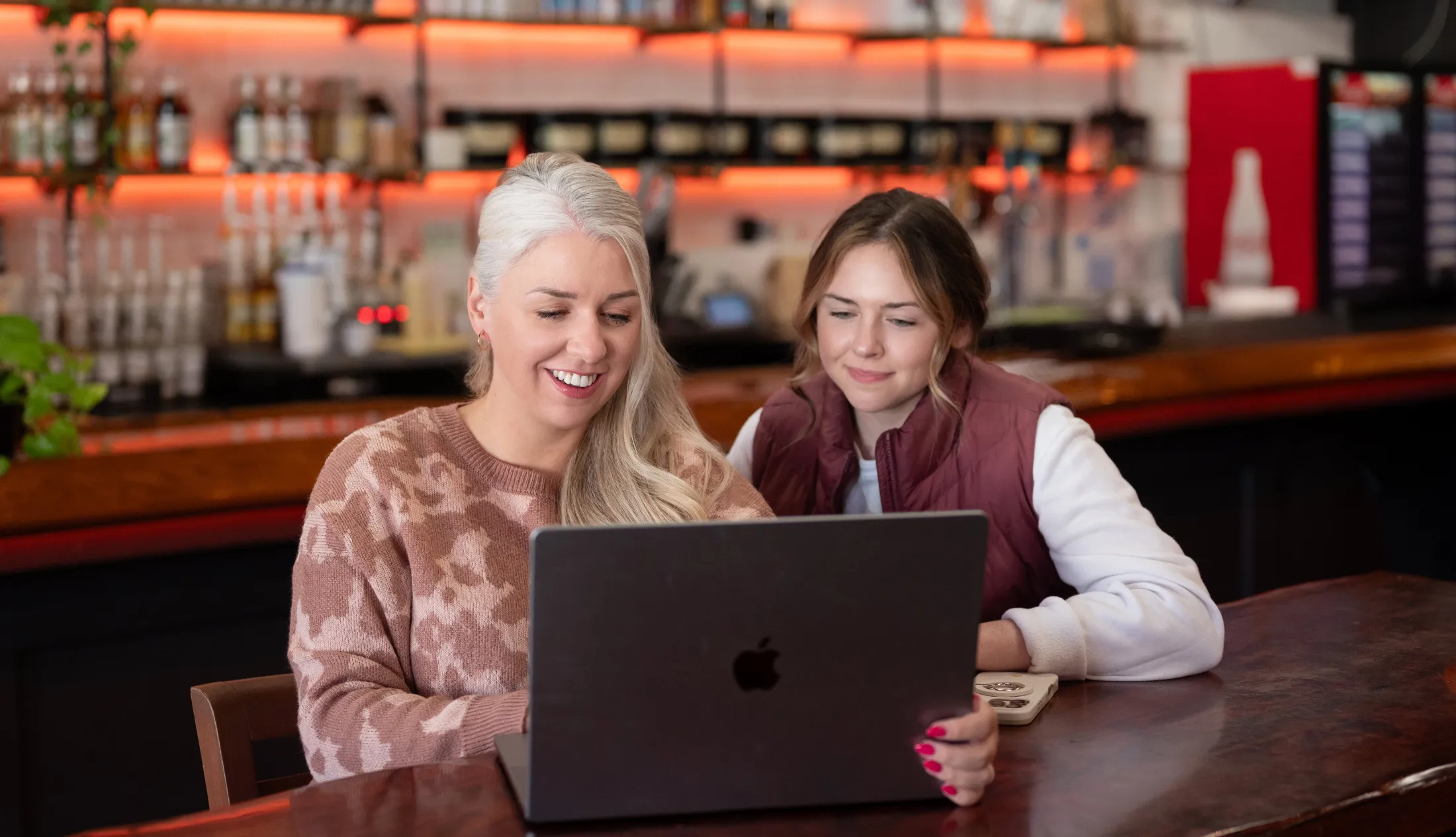 Two women reviewing content together on a laptop in a relaxed workspace setting