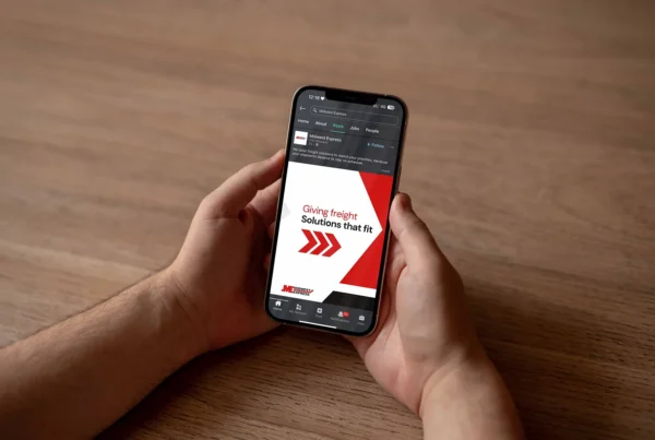 Person holding a smartphone displaying a Midwest Express social media post about freight solutions