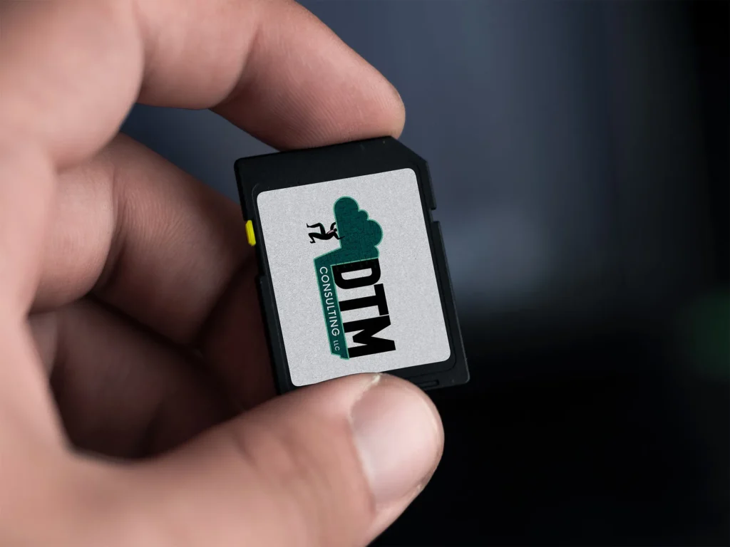 DTM Consulting LLC logo displayed on a small electronic device held between fingers