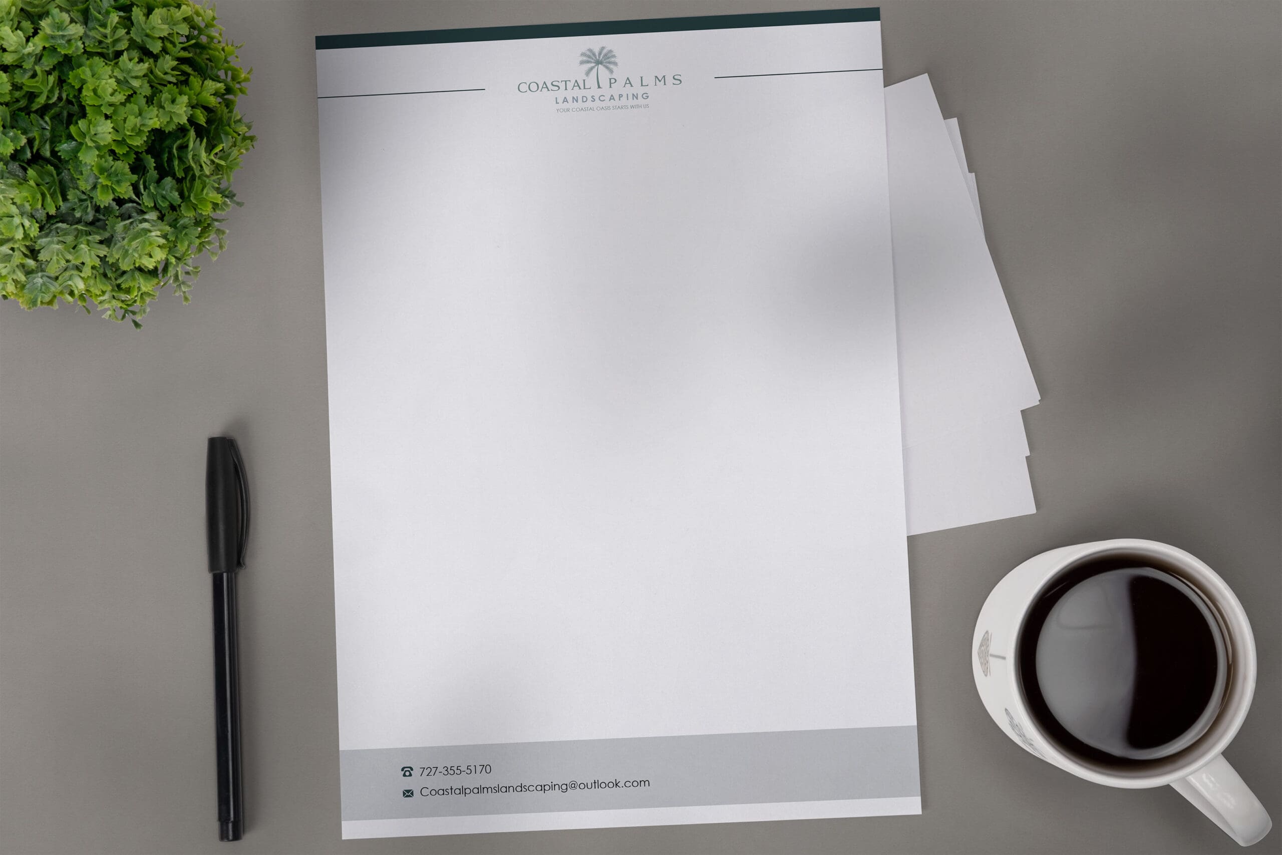 Coastal Palms Landscaping branded letterhead displayed on a modern desk with pen, plant, and coffee