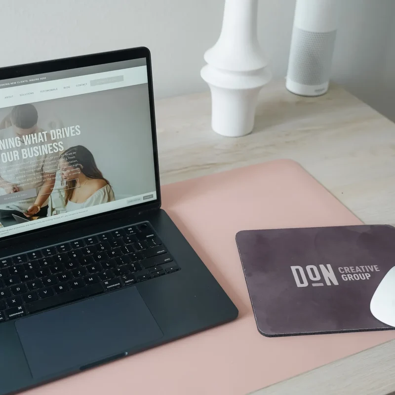 Laptop displaying a creative agency website on a modern desk with Don Creative Group branding