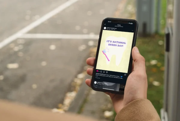 Hand holding smartphone displaying pediatric dental Instagram post for National Brush Day