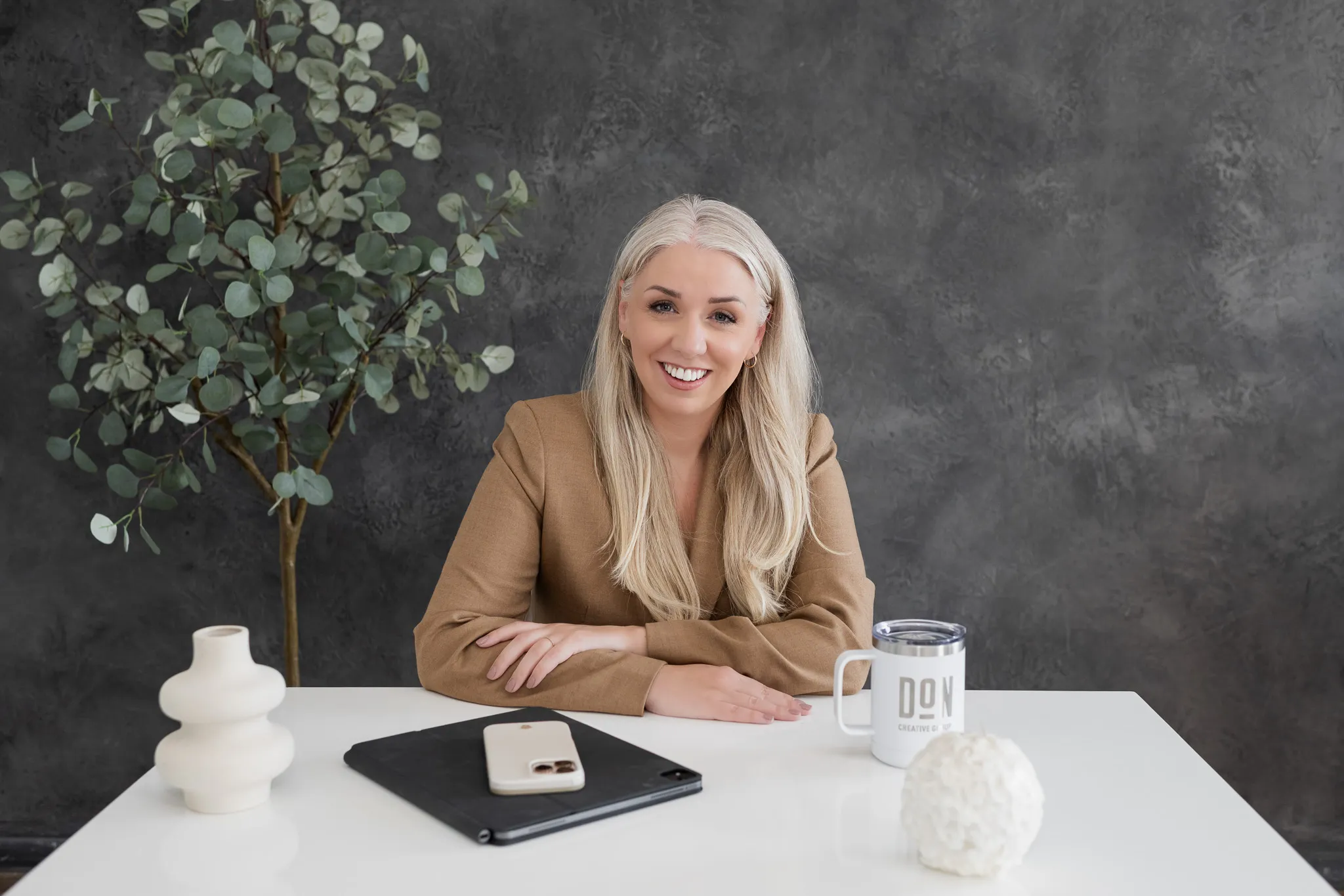 Smiling professional woman seated at a desk in a modern studio office setting
