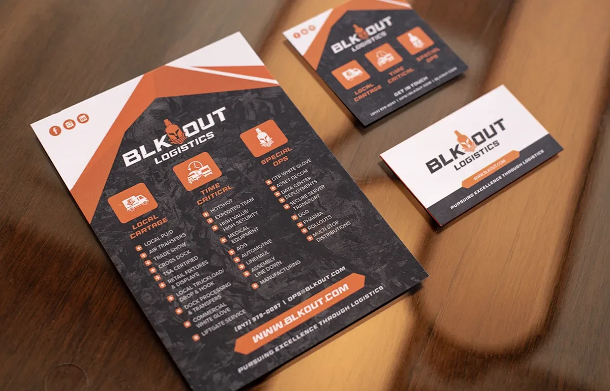 BLK Out Logistics flyer and business cards displayed on table showcasing services