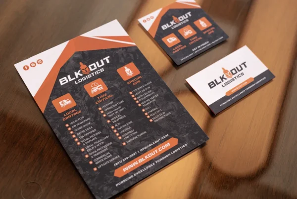 BLK Out Logistics flyer and business cards displayed on table showcasing services