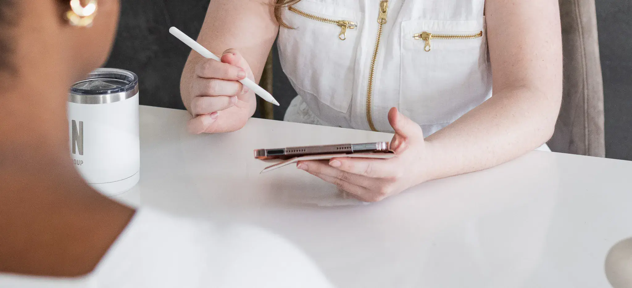 Team member holding tablet and stylus while discussing work across table