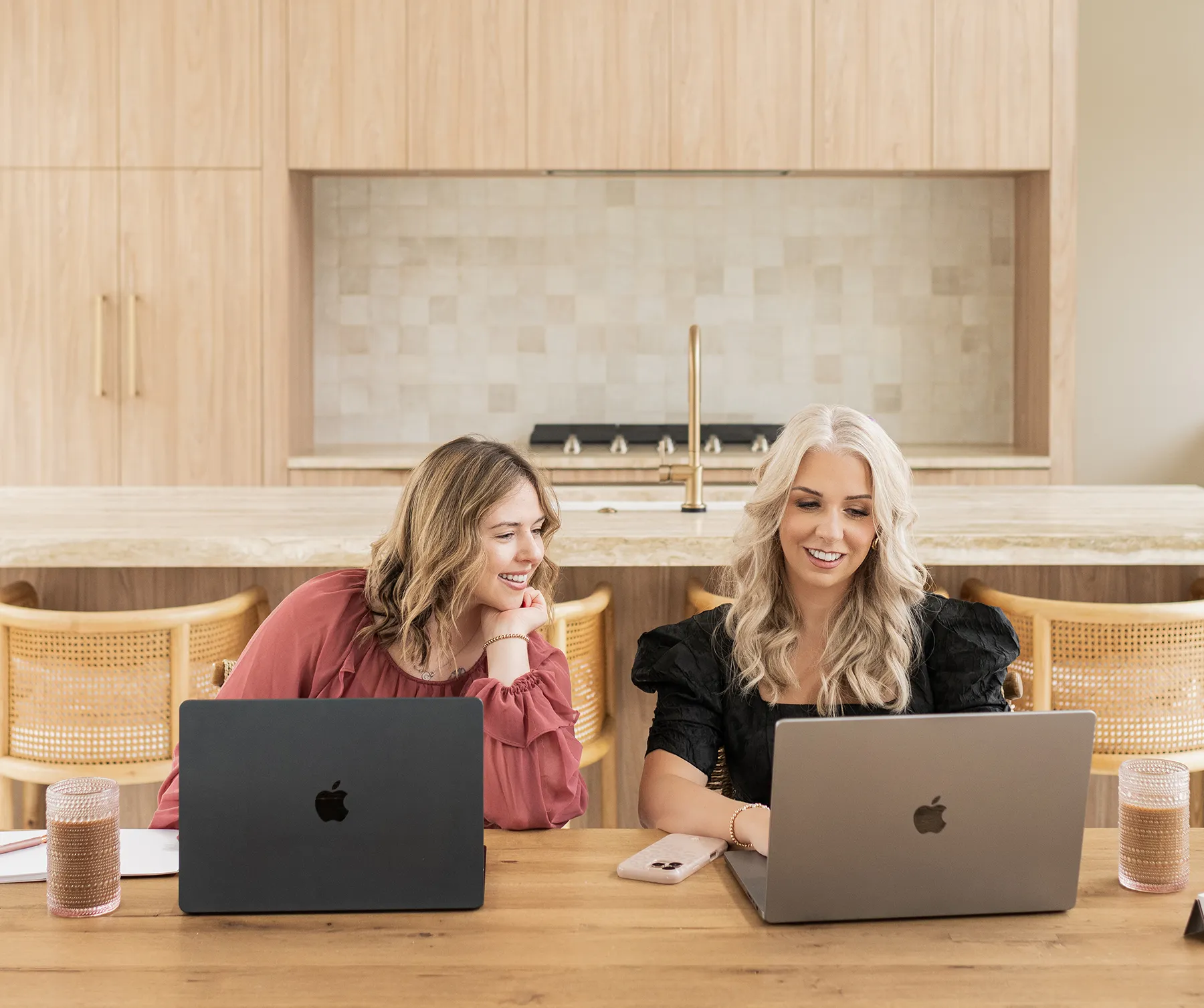 Two digital marketing professionals collaborating on laptops in a modern office while reviewing website strategy and online marketing performance.