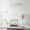 Minimalist office workspace with a laptop on a desk, soft pink chair, desk lamp, decorative plants, and a Don Creative Group wall sign in the background.